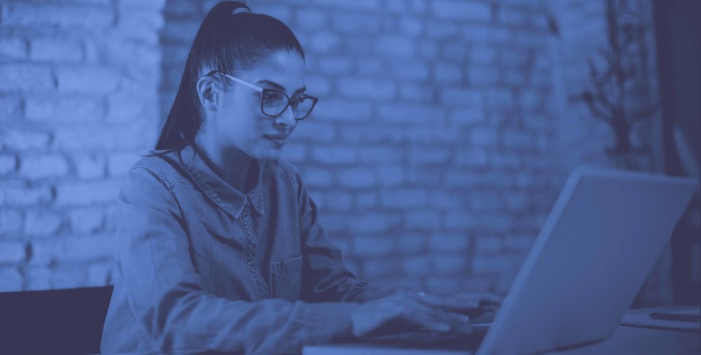 Woman With Ponytail and Glasses Sitting at Laptop Working
