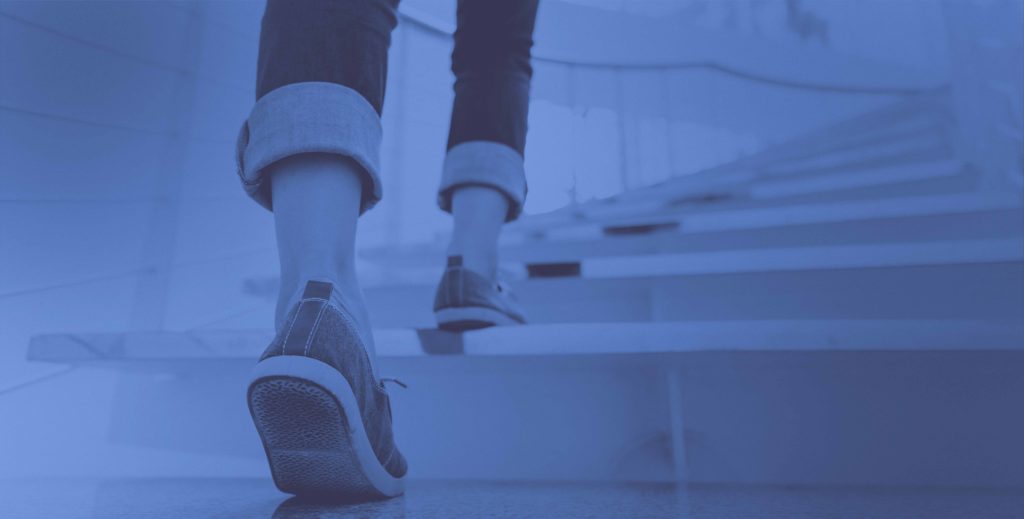 Woman's Feet in Sneakers and Jeans Walking Up Stairs Away From View