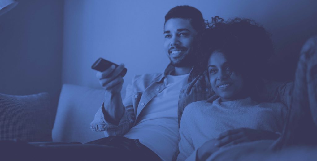 man and woman sitting on couch with remote watching TV