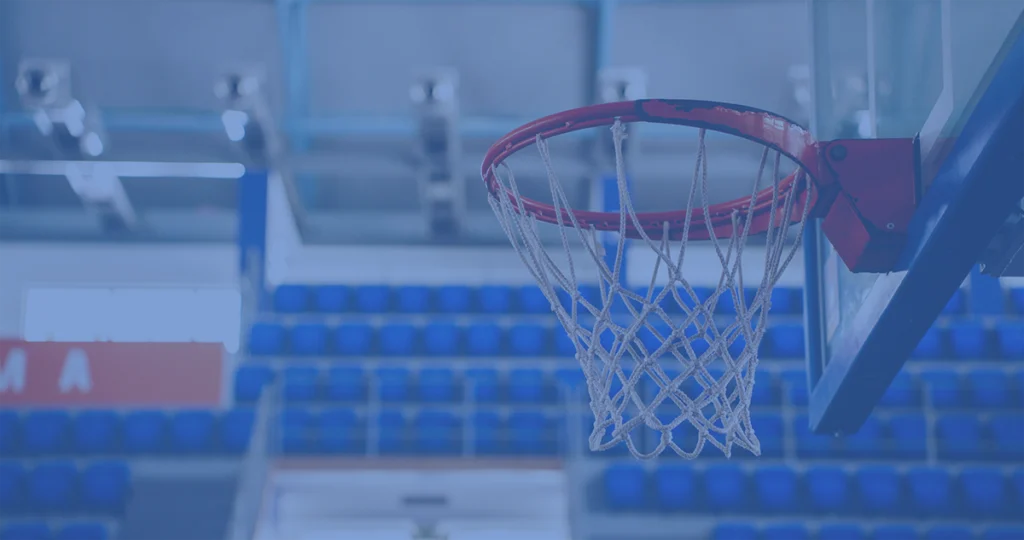 Basketball hoop and net in an indoor court with blue seating in the background.