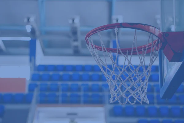 Basketball hoop and net in an indoor court with blue seating in the background.
